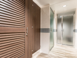 White tiled spa bathroom and shower featuring contrasting compact laminate partitions with traditional brown louver doors.