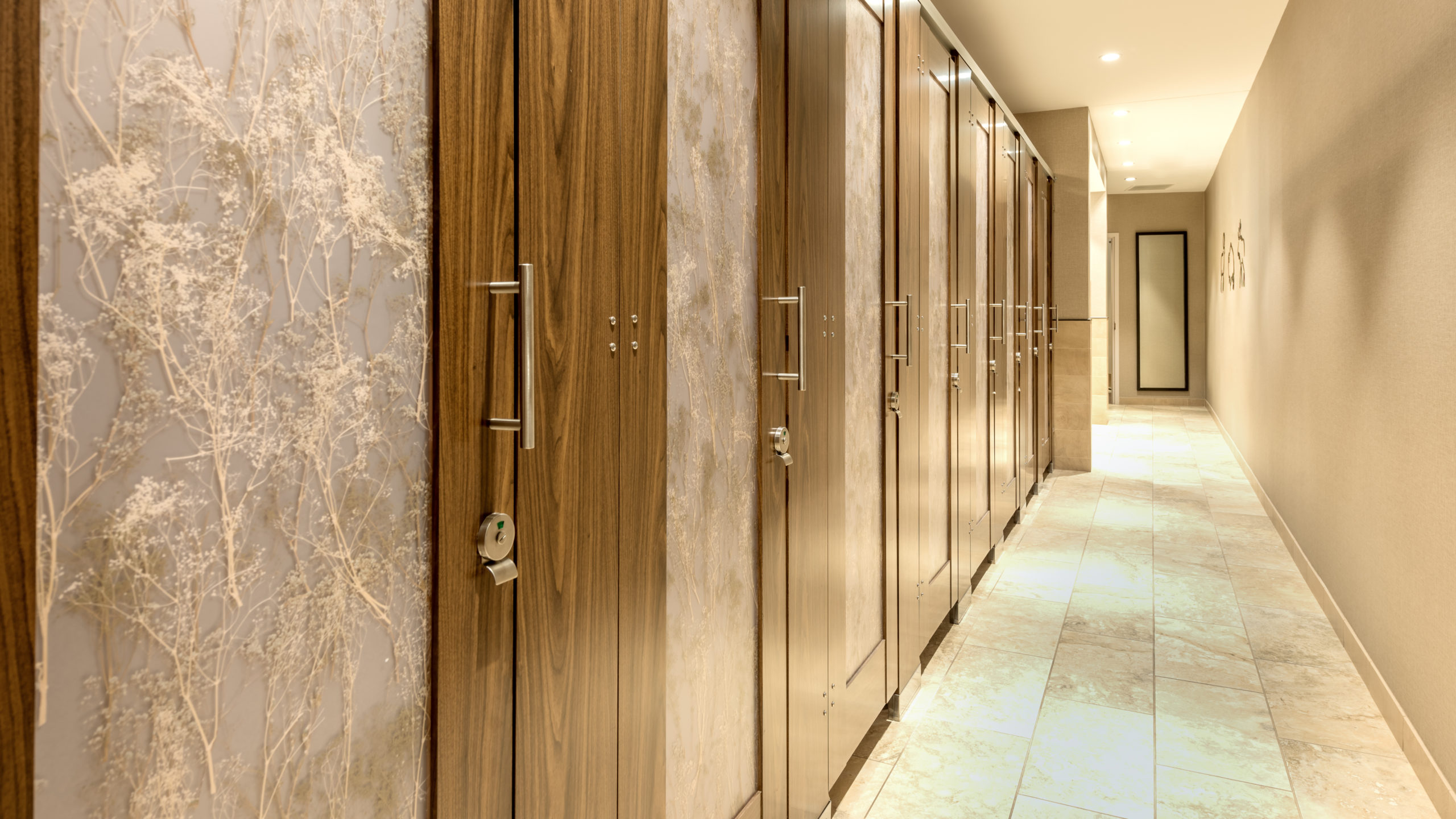Expansive wildlife museum bathroom features eight, high privacy laminate doors with baby’s breath design on translucent acrylic door lite inserts.