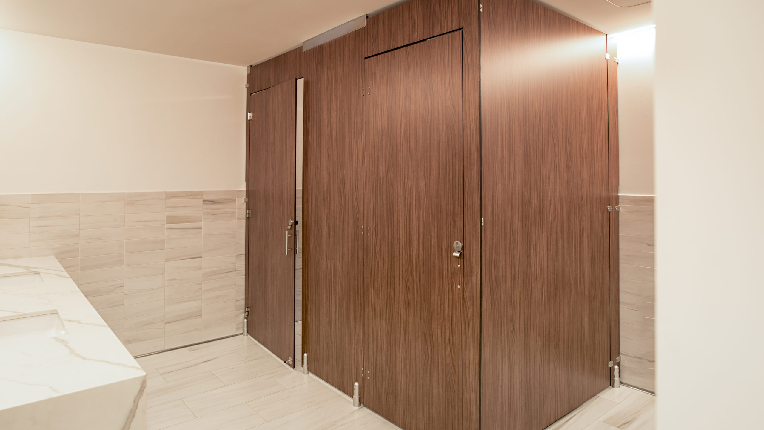 Executive office employee bathroom in compact laminate partitions with full height configuration showing transoms for added privacy.