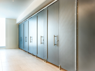 Executive club bathroom with six European zero sightline solid surface partitions featuring 16” stainless steel bar pulls and pedestal footholds.