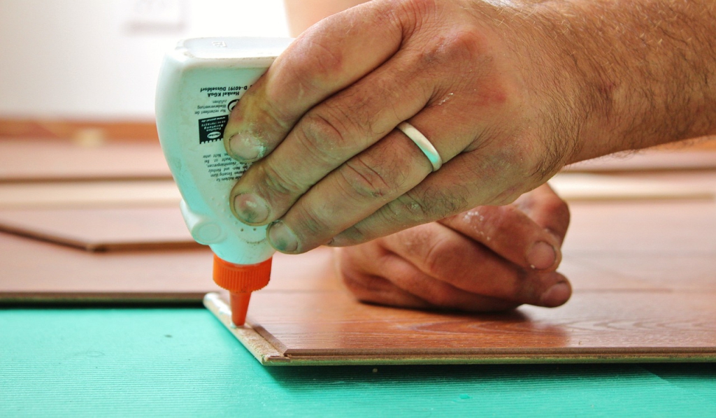A person applying adhesive to a piece of wood.