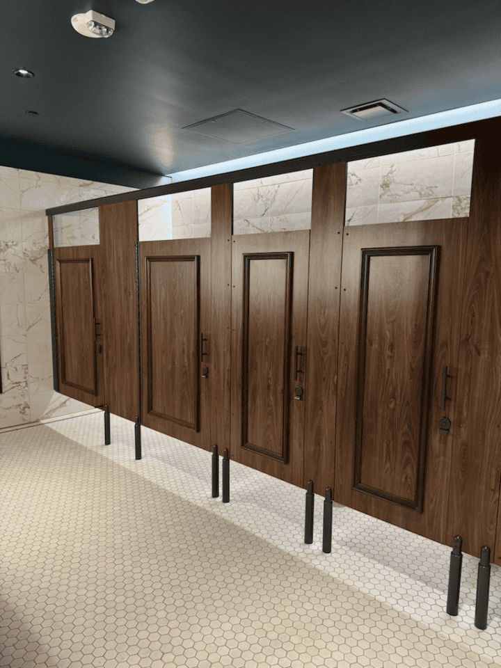 Commercial restroom with compact laminate partitions, applied moldings, powder coated hardware and European mounting (headrail and pedestals).