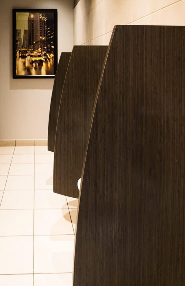 Custom shape commercial restroom urinal screens in a woodgrain plastic laminate.
