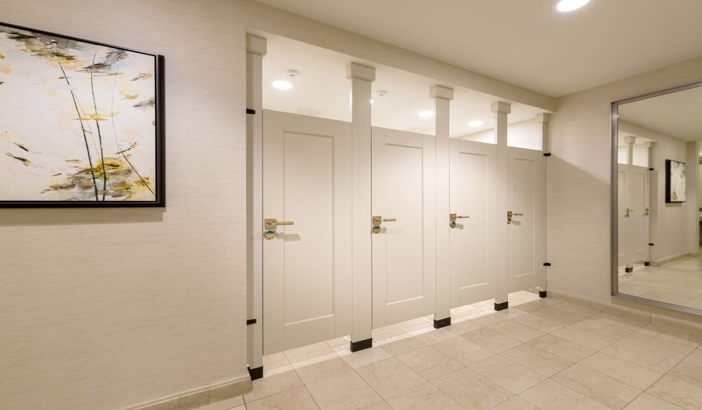 A bathroom with two stalls featuring floor to ceiling toilet partitions.