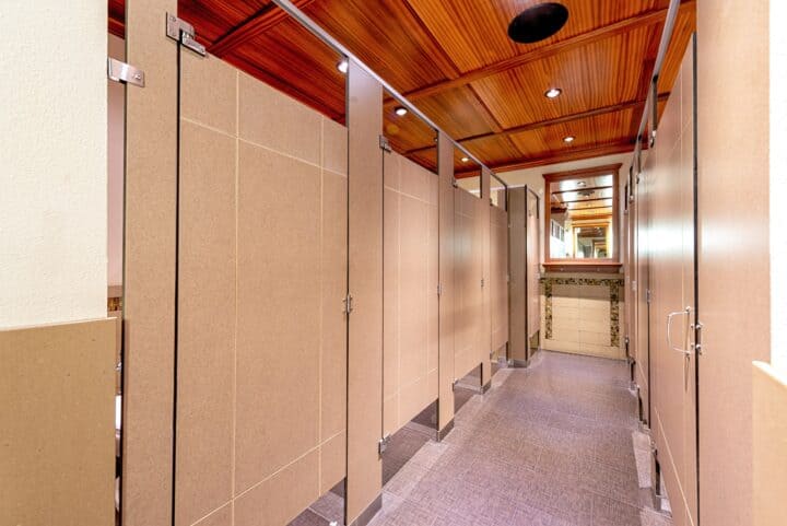 Toilet partitions with engraving in compact laminate mounted headrail braced, with a mirror at the end of the room.