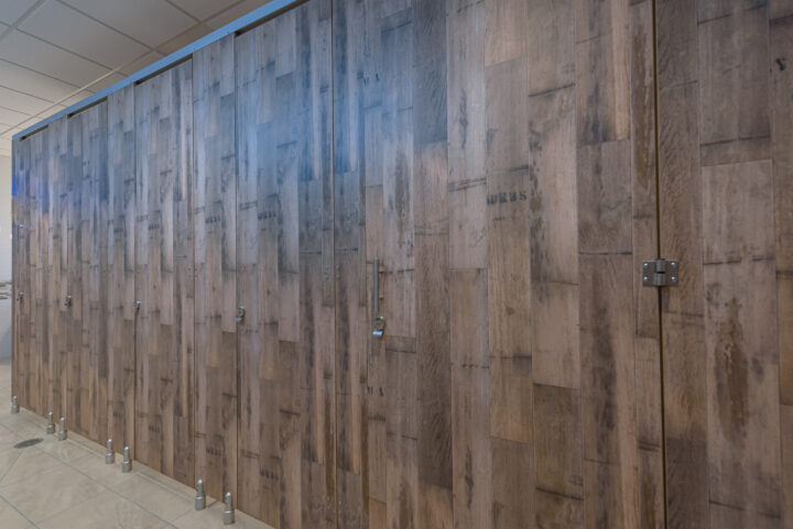 High pressure laminate flat panel toilet partitions with indicator latches, headrail, and pedestals.