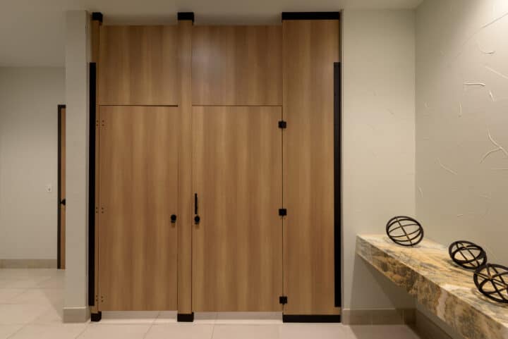 A modern restroom with high pressure laminate, flat panel doors, floor-to-ceiling mounted, with powder coated full length hardware.