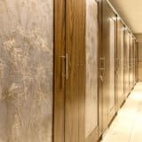 A restroom with a row of stalls made of high pressure laminate, headrail braced, with 3form acrylic door lites.
