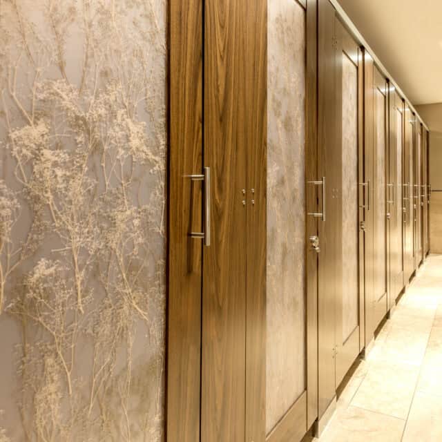 A restroom with a row of stalls made of high pressure laminate, headrail braced, with 3form acrylic door lites.