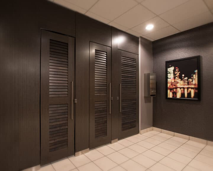 Commercial restroom with modern high pressure laminate louvered partitions with long pulls and transoms. Floor to ceiling mount. Picture on the right.