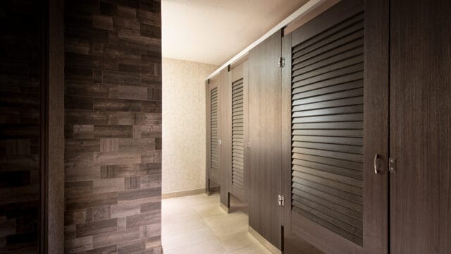 High pressure laminate louvered public restroom partitions mounted headrail braced.