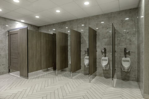 A row of urinals in a public bathroom, featuring urinal screens for added privacy and hygiene.