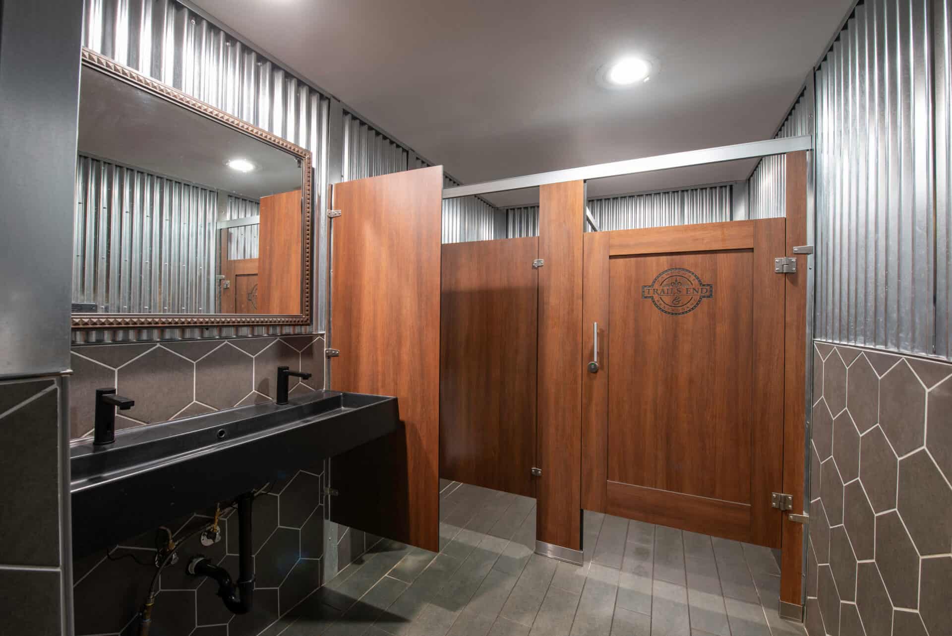 Restaurant restroom partitions made from compact laminate with captured panel doors and custom engraving.