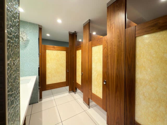 Floor To Ceiling toilet partitions in Wood Veneer with zero sightline and door lites for a restaurant application. Image by Ironwood Manufacturing.