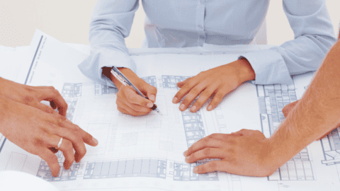 Collaborative planning session with architects and designers reviewing restroom layout blueprints for a commercial space.