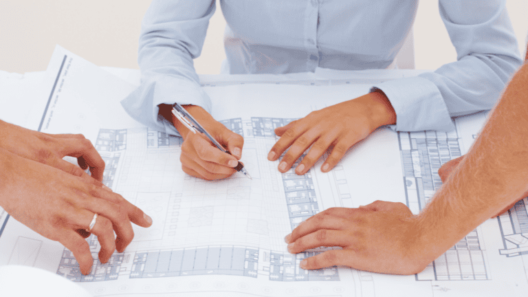 Collaborative planning session with architects and designers reviewing restroom layout blueprints for a commercial space.