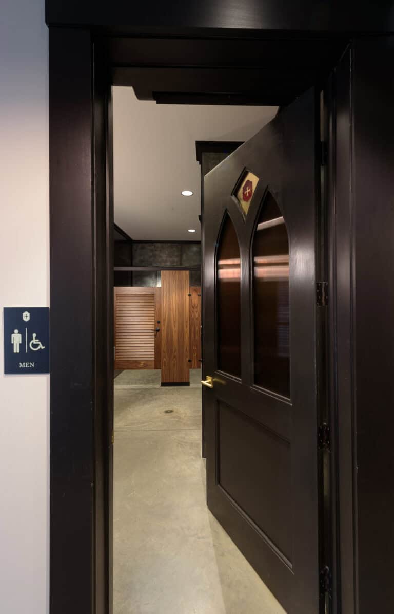 Restroom entry highlighting dark wood doors, accessibility signage, and custom wood grain partitions for commercial use.