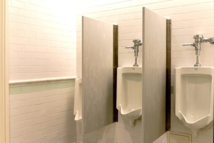 Two white solid surface urinal screens with continuous wall brackets.