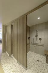 Compact laminate shower stall with woodgrain panels and floor mounted supports in a private changing area.