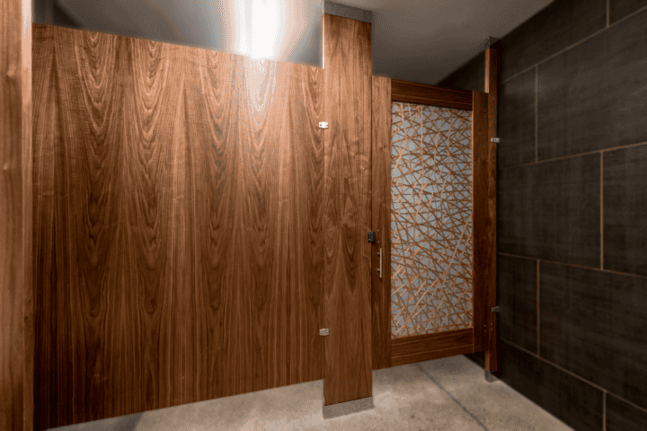 Wood veneer upscale ADA accessible toilet partition with acrylic door lites and floor to ceiling mounting.