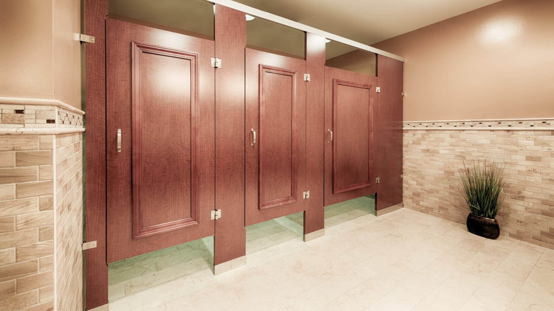 A commercial restroom with three partitions in high pressure laminate, headrail braced, with applied moldings on the doors.