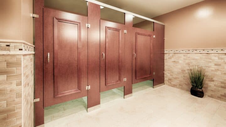 A commercial restroom with three partitions in high pressure laminate, headrail braced, with applied moldings on the doors.